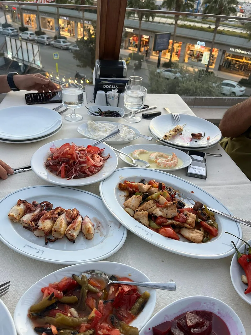 Kalamar ızgara, tereyağlı karides, sote ve domatesli biber mezeleriyle bulvara bakan masa
